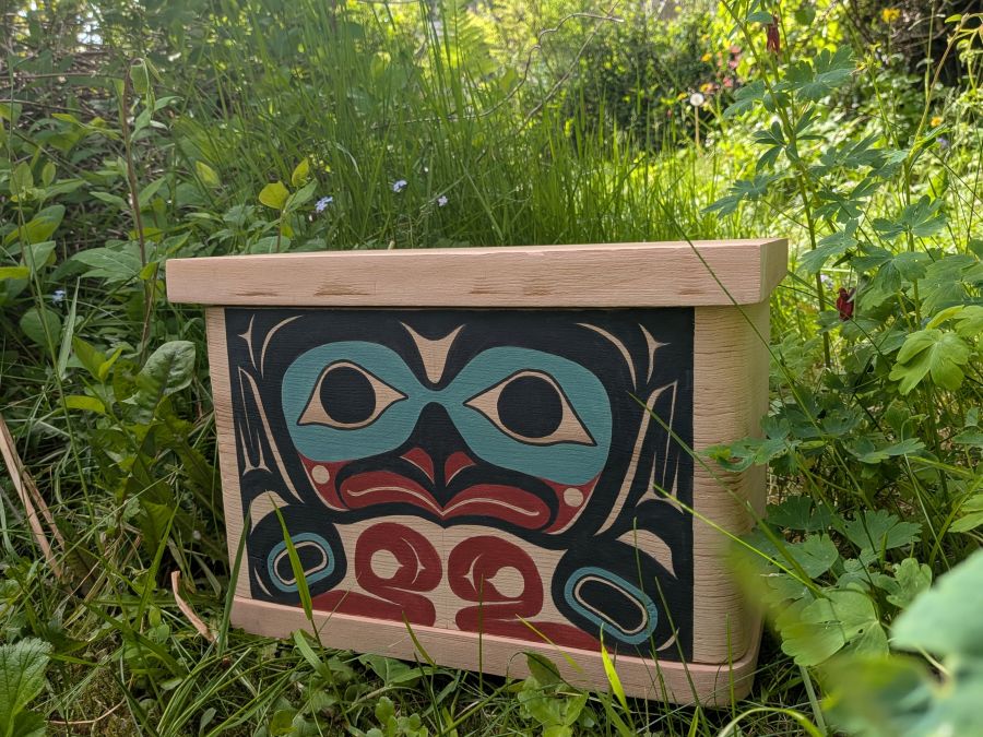 A red cedar bentwood box with a formline eagle painted on the front in black, red, and teal.